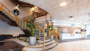 A modern hotel lobby with a curved staircase, a reception desk, and a seating area. - The Bolton Stadium Hotel, a member of Radisson Individuals (Bolton)