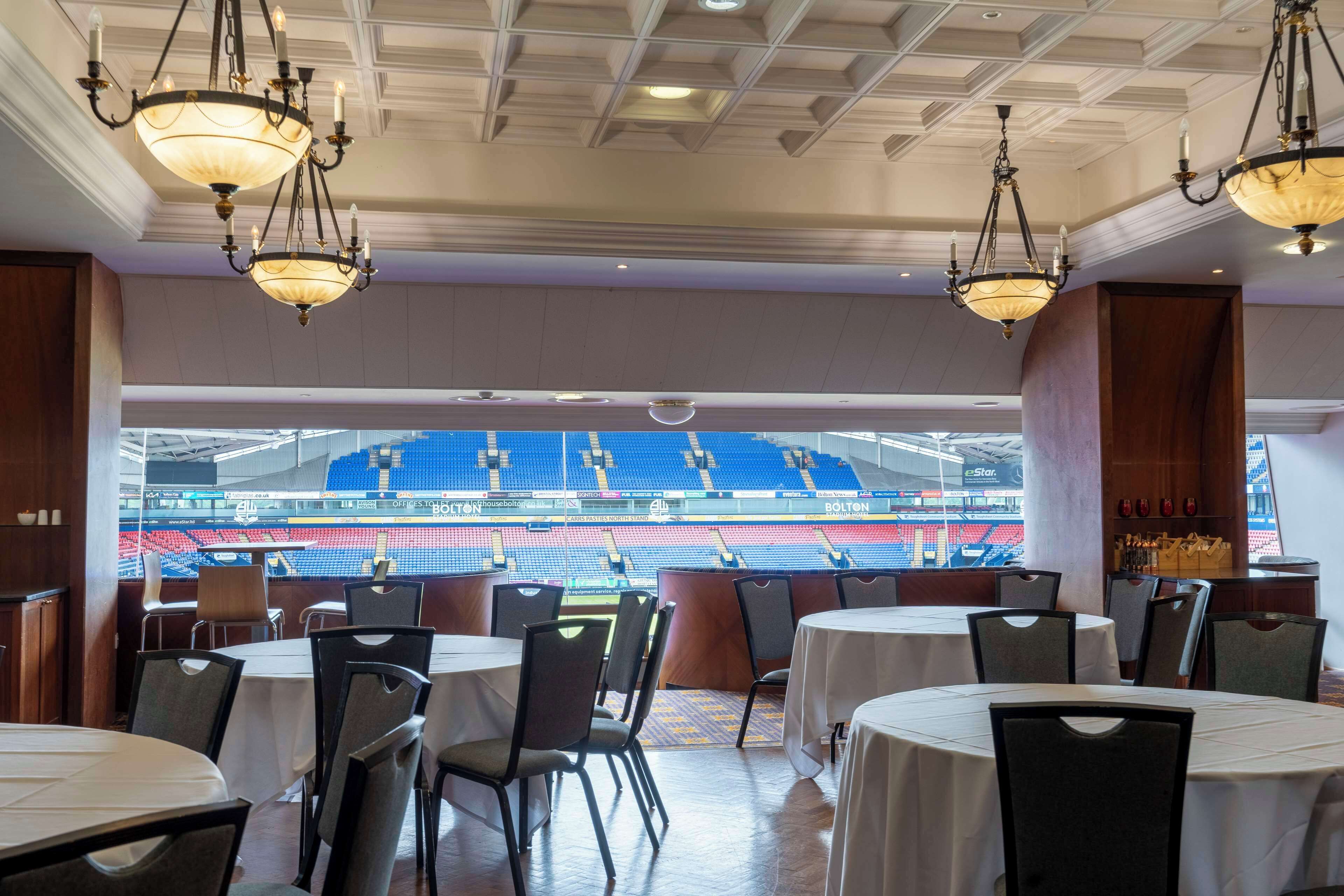 Un restaurante con mesas y sillas, vista hacia un estadio y candelabros.