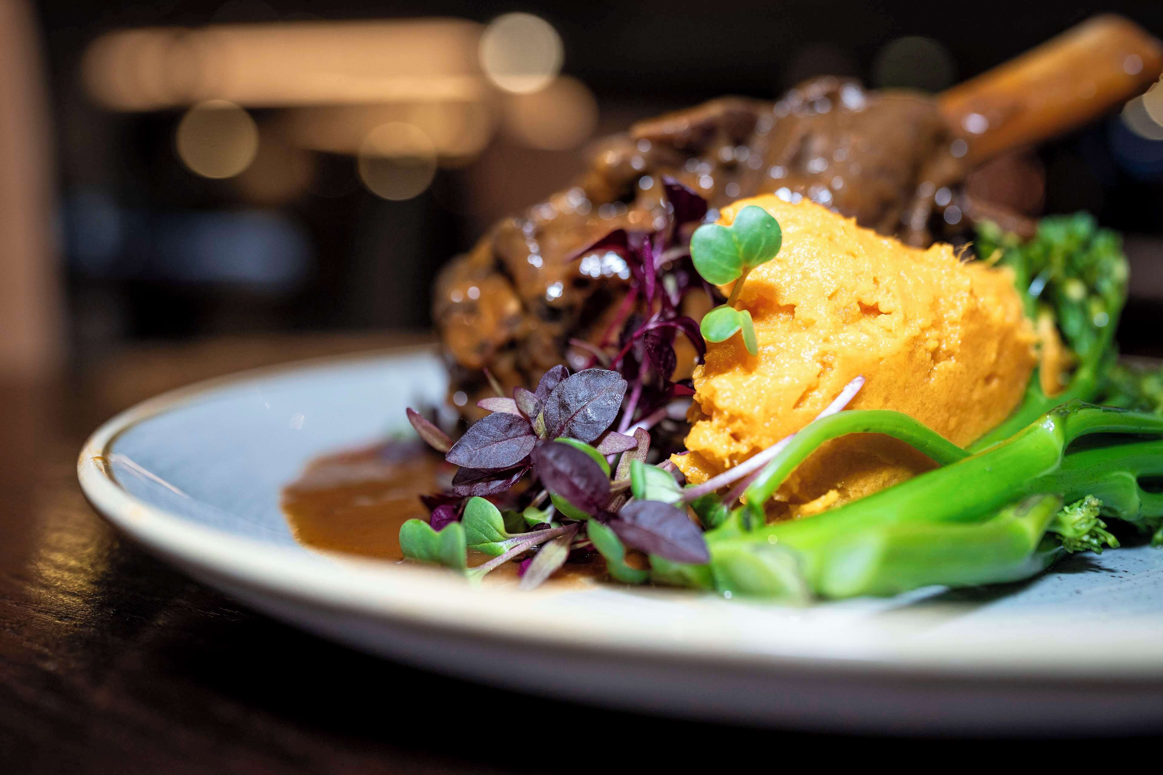 A plate of food with a piece of meat, mashed potatoes, and greens.