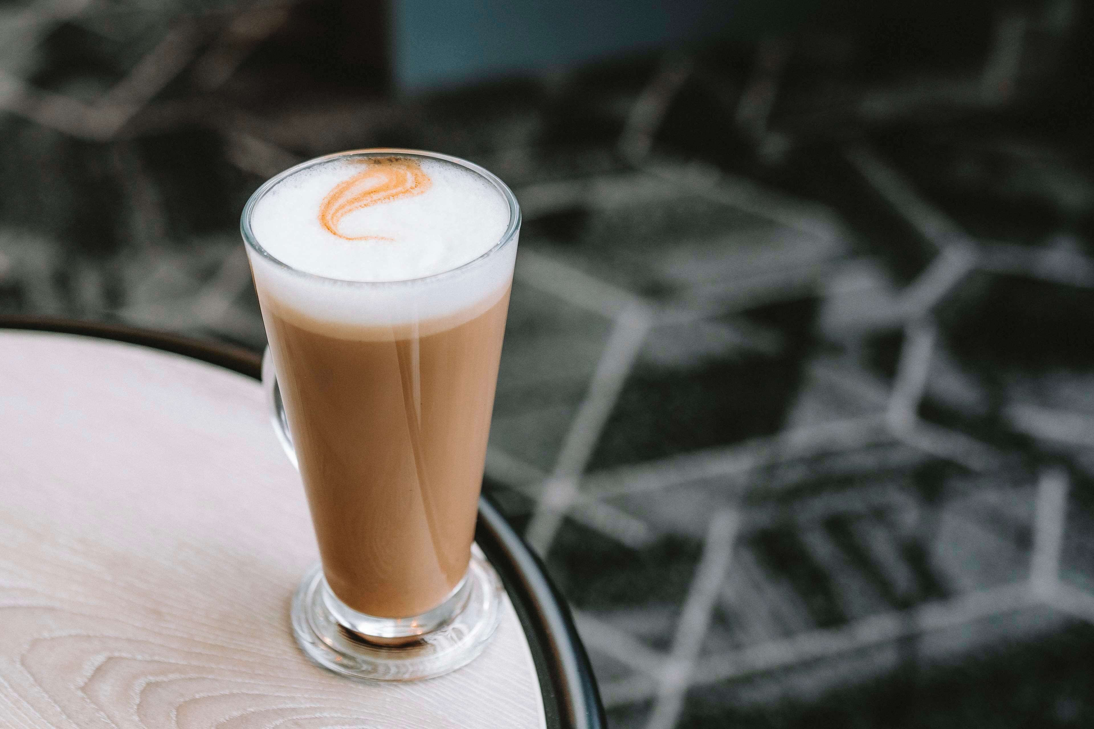 Un vaso de café helado con arte de latte sobre una mesa.