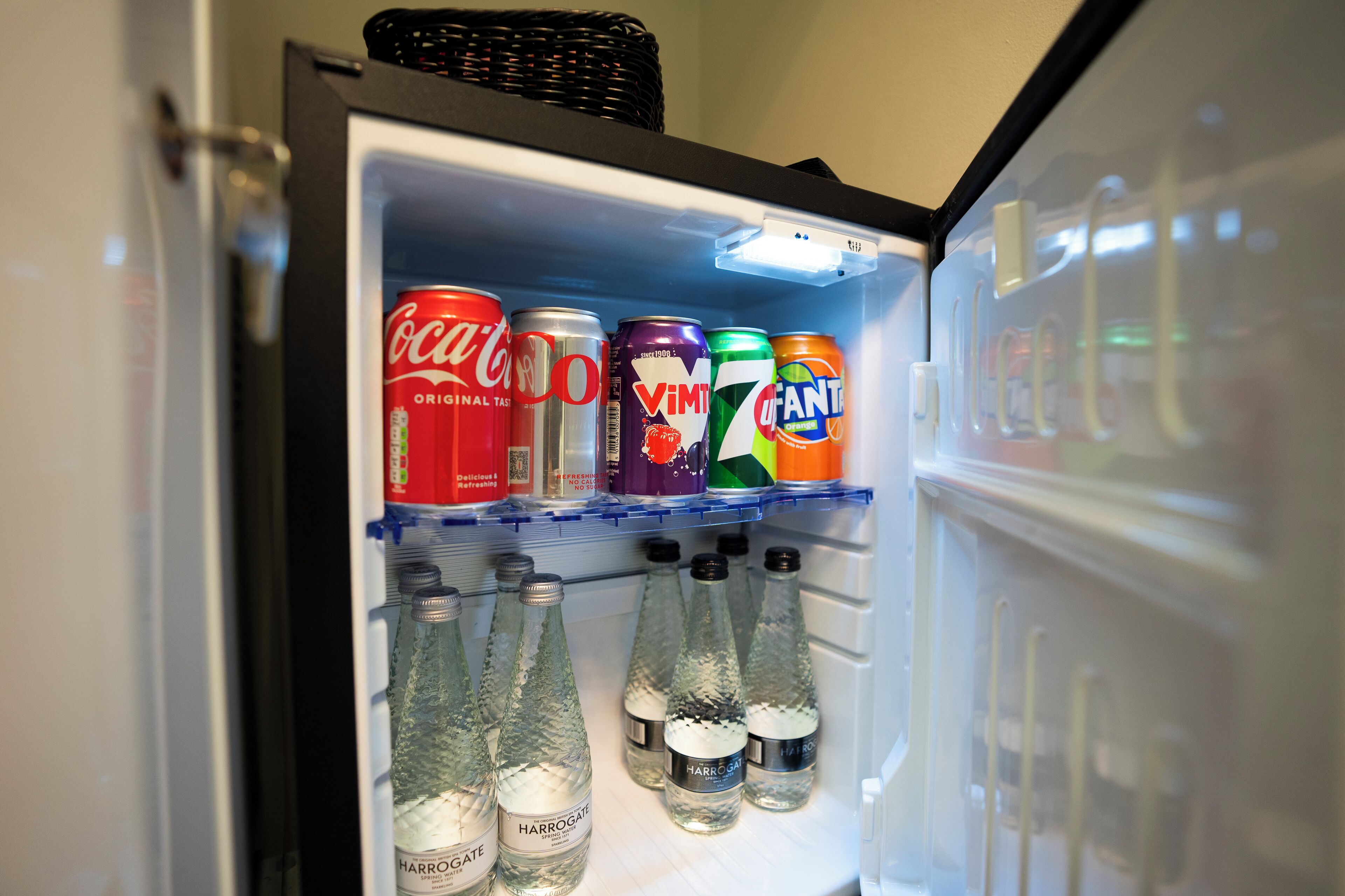 A refrigerator with beverages including Coca-Cola, V8, and Fanta.
