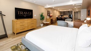 Une chambre d’hôtel avec un grand lit, une télévision, un bureau et une kitchenette.