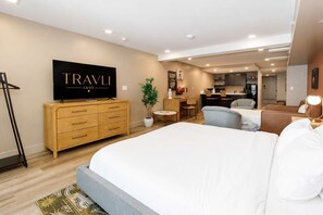 Ein Hotelzimmer mit einem großen Bett, einem Fernseher, einem Schreibtisch und einer Küchenzeile.