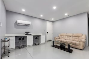 Ein modernes Zimmer mit einem weißen Schreibtisch, einem beigen Sofa und einem Glastisch.