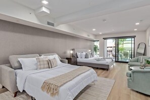 Relax in a spacious bedroom with a large bed, sofa, and chair, offering a comfortable seating area and a balcony with a view.
