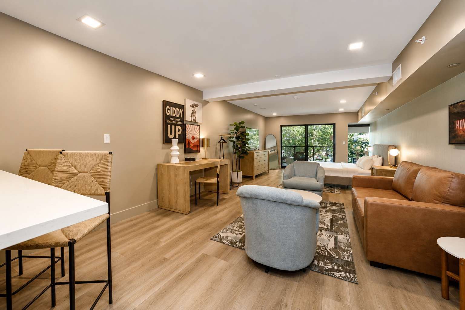 A modern living room with a dining area, a sofa, a coffee table, and a large window with a view of greenery.