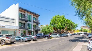 A street view with parked cars, a building with balconies, and trees. - NEW|Luxe Ocotillo Suite @ Cedara|Heart of Old Town (Scottsdale)