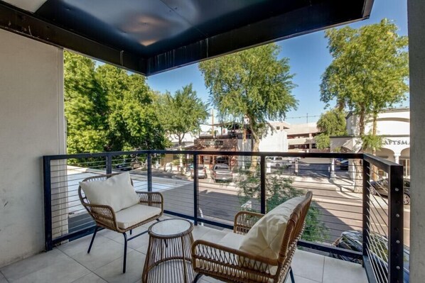 Enjoy the serene view from this balcony with a street view, featuring two comfortable chairs and a small table.