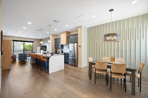 A modern kitchen with a central island, stainless steel appliances, and a dining area with a chandelier.
