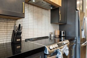 A modern kitchen with a stainless steel range, a built-in oven, a coffee maker, and a knife block.