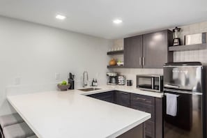 A modern kitchen with a central island, stainless steel appliances, and dark cabinetry.