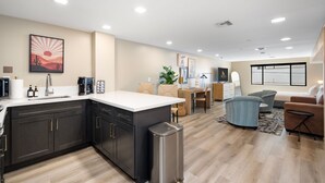 A modern kitchen with dark cabinets, a stainless steel trash bin, and a coffee machine. - NEW|Luxe Cypress Suite @ Cedara |Heart of Old Town (Scottsdale)