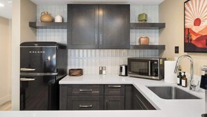 A modern kitchen with dark cabinetry, a black refrigerator, a microwave, and a sink. - NEW|Luxe Cypress Suite @ Cedara |Heart of Old Town (Scottsdale)