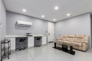 Ein modernes Zimmer mit einem weißen Schreibtisch, einem beigen Sofa und einem Glastisch.