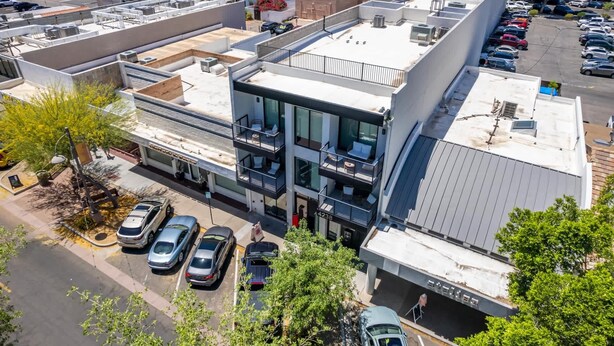 Un edificio de varios pisos con techo plano, ventanas grandes y un estacionamiento.
