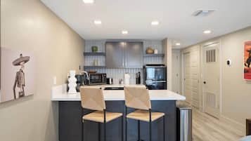 Una cocina moderna con una isla central, taburetes de bar y un refrigerador.
