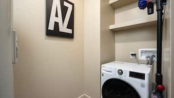 A laundry room with a washing machine, a wall-mounted heater, and a shelf with a letter 'AZ' sign.
