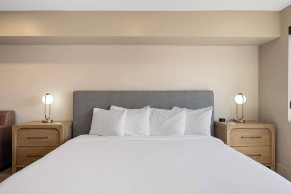 Una habitación de hotel con una cama grande, dos mesitas de noche y dos lámparas de pared.