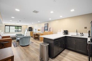 A modern kitchen with a central island, a dining area with a sofa and chairs, and a living room with a couch and a coffee table.