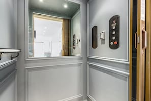 Ein moderner Aufzug mit Bedienfeld, Spiegel und Fenster mit Außenblick.