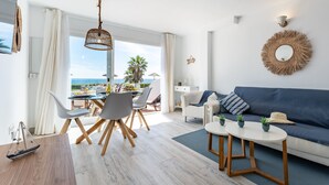En moderne stue med sofa, spisebord, stole og havudsigt.