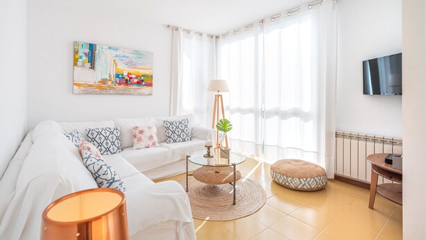 A modern living room with a sofa, a glass coffee table, a lamp, and a television. - "Apartamento Mirella" with Pool, Balcony, and Wi-Fi (port de pollença)