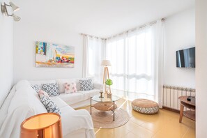 A modern living room with a sofa, a glass coffee table, a lamp, and a television.