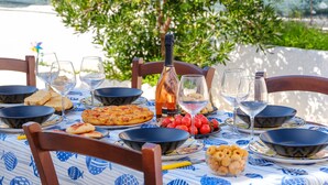 A table set with plates, glasses, a bottle, and food items, with a view of greenery in the background. - Holiday Accommodation "Villa Grecale" with garden and walking distance to the sea (Porto Cesareo)