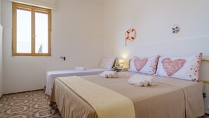 A hotel room with a bed, a bedside table, a lamp, a window, and a wall decoration. - Holiday Accommodation "Villa Grecale" with garden and walking distance to the sea (Porto Cesareo)