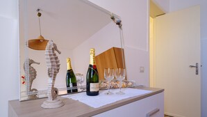 A room with a wooden dresser, a mirror, a bottle of champagne, two wine glasses, and a decorative seahorse sculpture. - Holiday Accommodation "Villa Grecale" with garden and walking distance to the sea (Porto Cesareo)