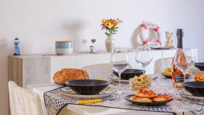 A dining table with a loaf of bread, bowls, wine glasses, and a bottle of wine. - Holiday Accommodation "Villa Grecale" with garden and walking distance to the sea (Porto Cesareo)