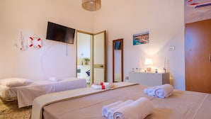 Ein Hotelzimmer mit zwei Betten, einem Fernseher, einem Spiegel, einem Schreibtisch mit Lampe und einer Rettungsboje als Dekoration.