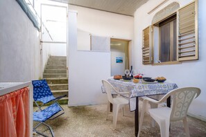A dining area with a table set for two, a window with blinds, and a staircase leading to an upper level.