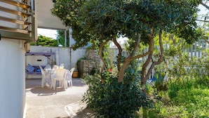 Ein Patio mit Tisch und Stühlen, eine Steinmauer und ein Baum.