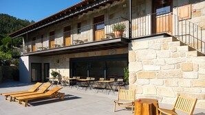 A stone building with a balcony, outdoor seating, and a view of the surrounding area. - Casa Vieira Lobo (Arouca)