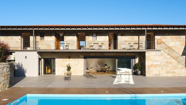 A modern building with a pool, outdoor seating, and a stone facade. - Casa Vieira Lobo (Arouca)