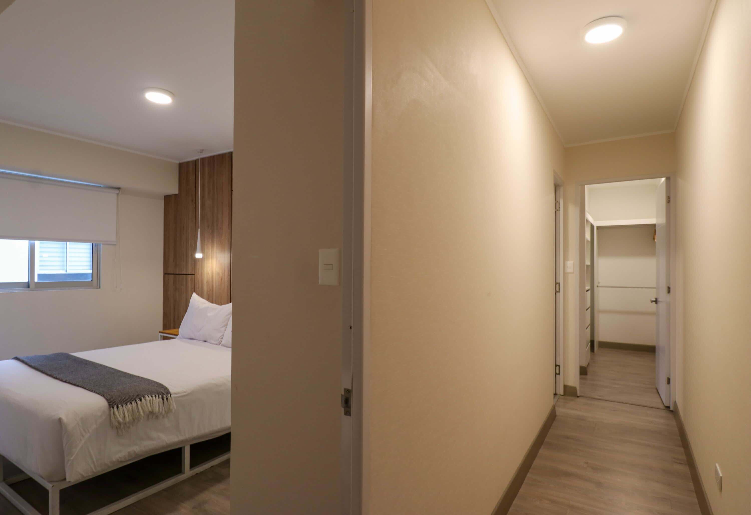 Una habitación de hotel moderna con cama, mesita de noche y vestidor.