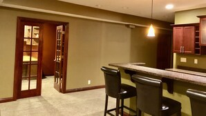 Une cuisine avec un coin bar, des meubles de rangement en bois et un luminaire au plafond.