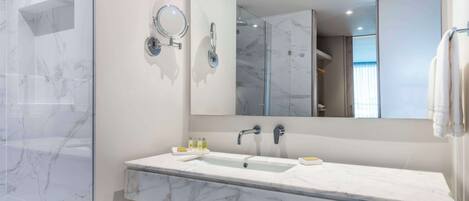 Un baño moderno con lavamanos de mármol, un espejo grande y cabina de ducha de vidrio.