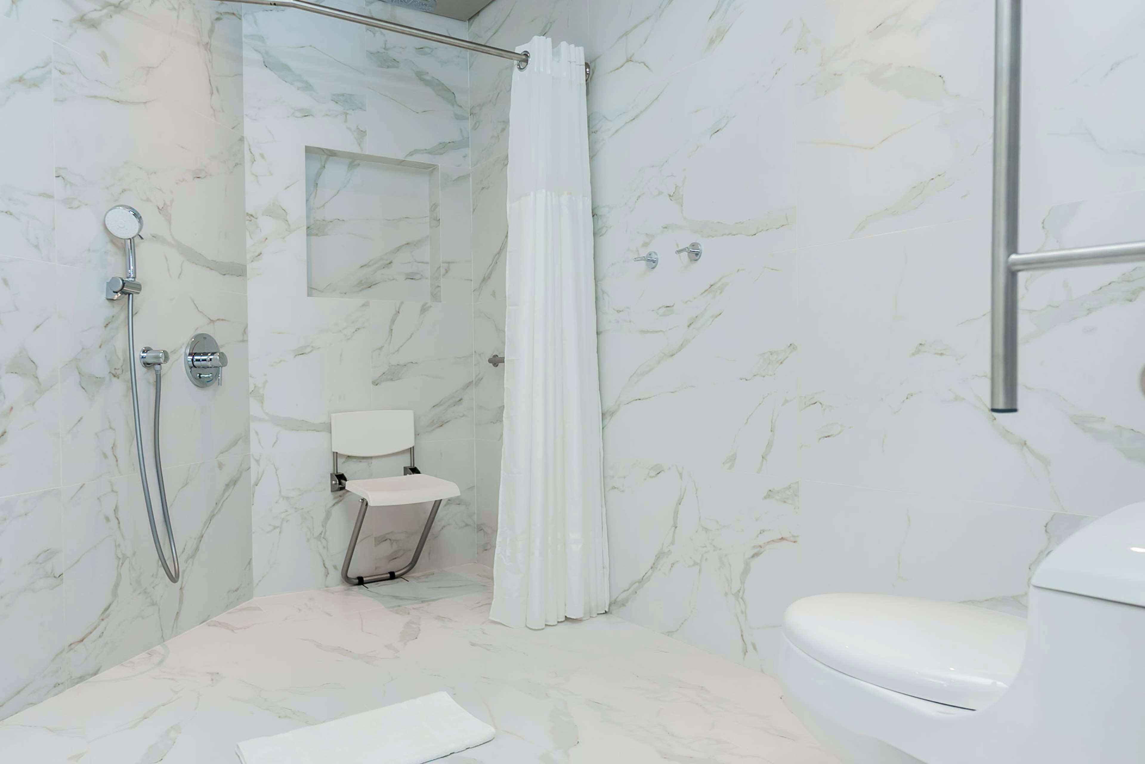 A bathroom with a shower, toilet, and a small sink.