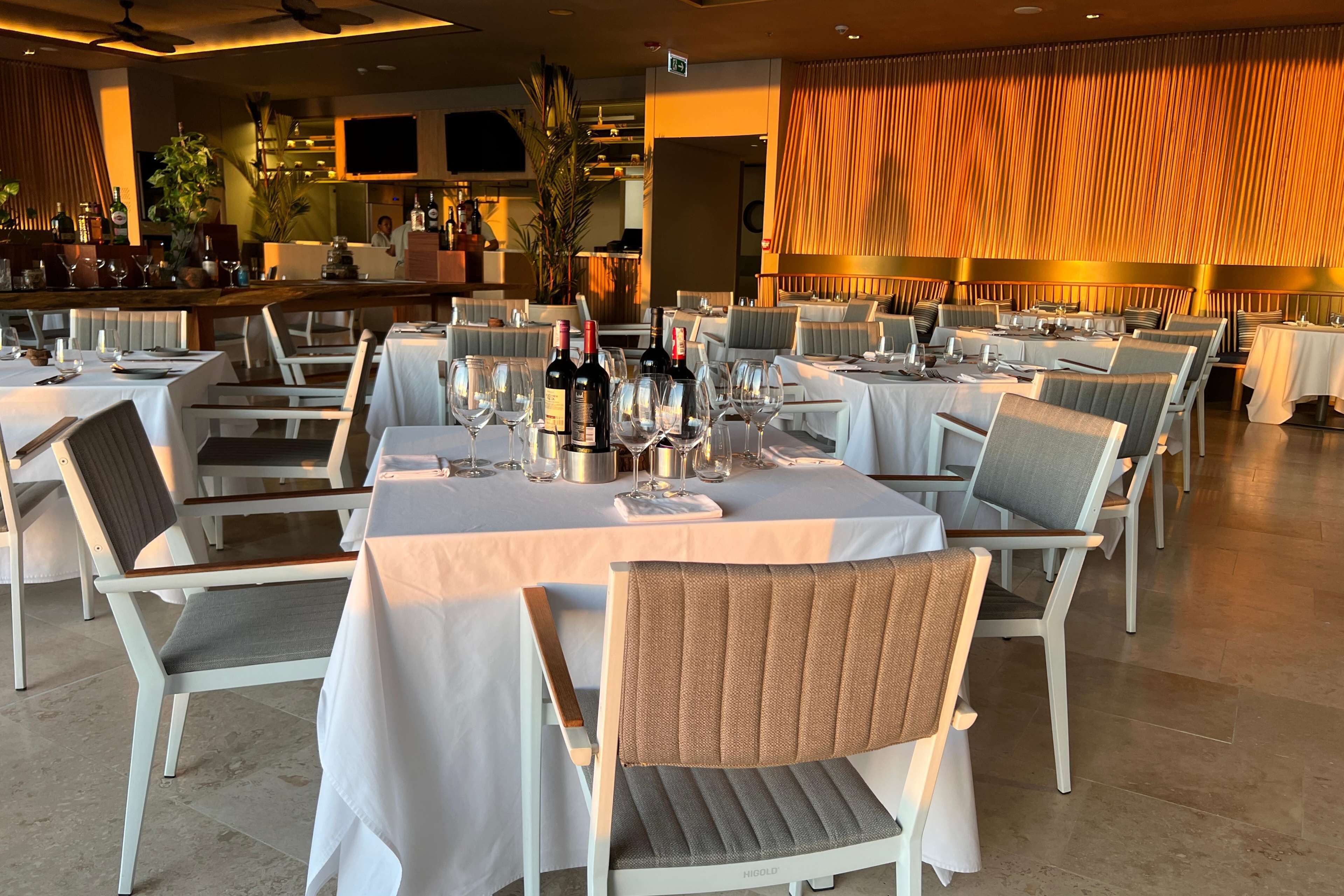 A restaurant with multiple tables set for dining, each with chairs and wine glasses.