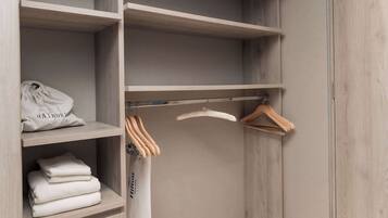 Un armario con estantes de madera, una barra para colgar ropa y toallas dobladas con cuidado.