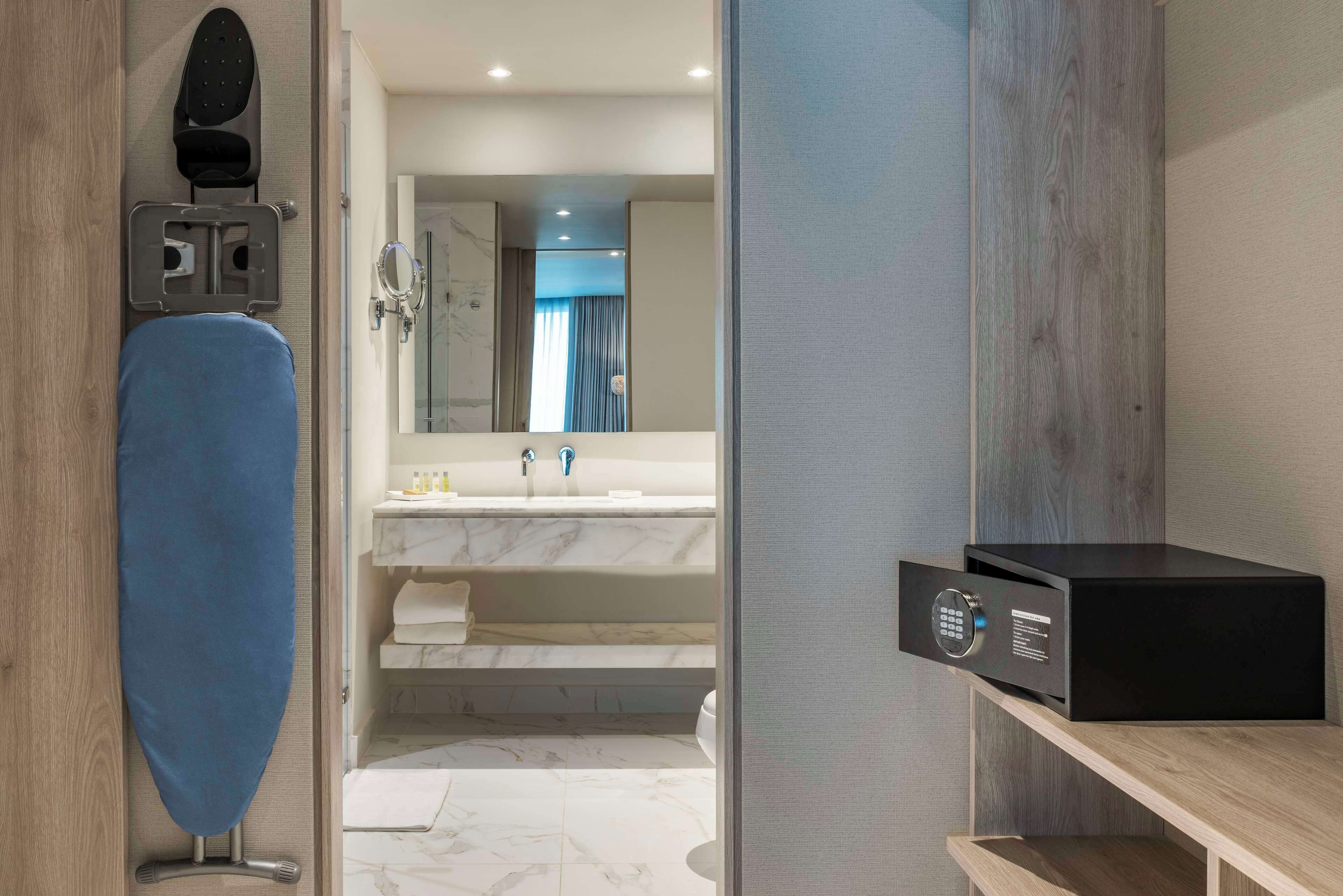 A modern bathroom with a marble sink, a mirror, and a black storage unit.