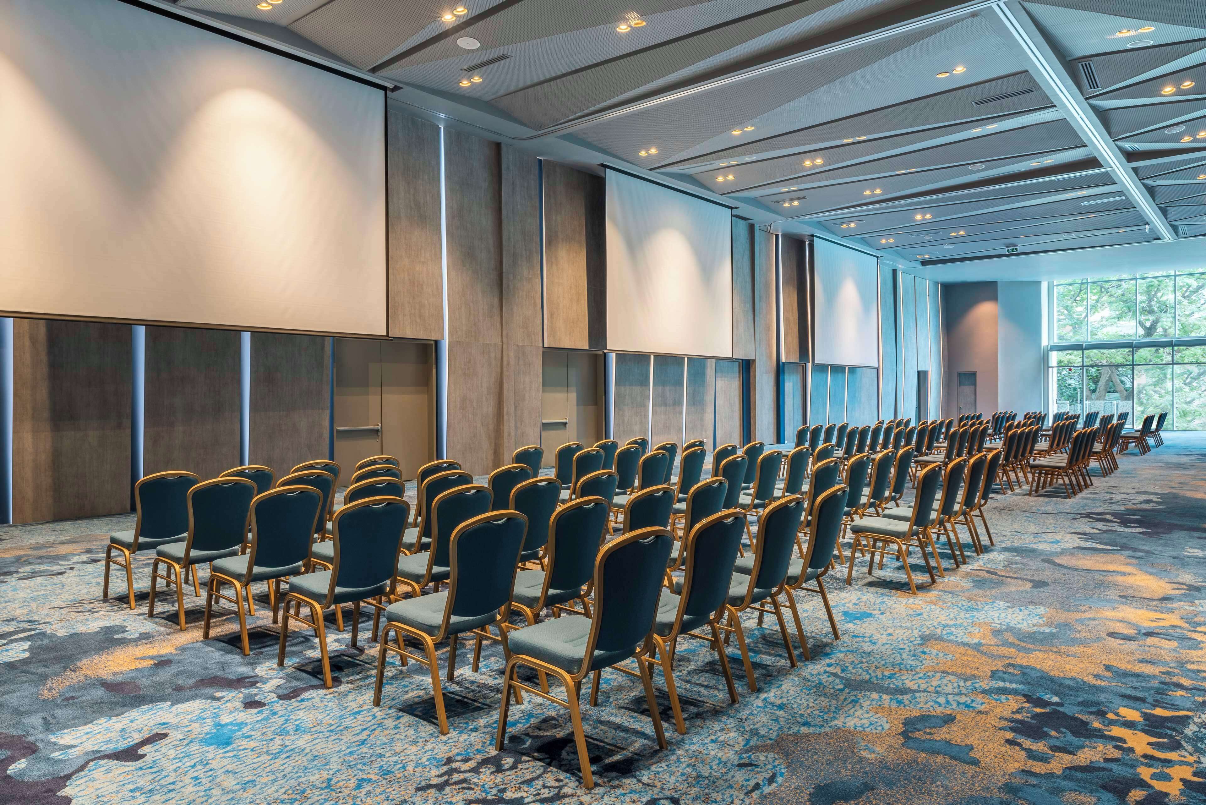 A conference room with rows of chairs, a patterned carpet, and a large window.