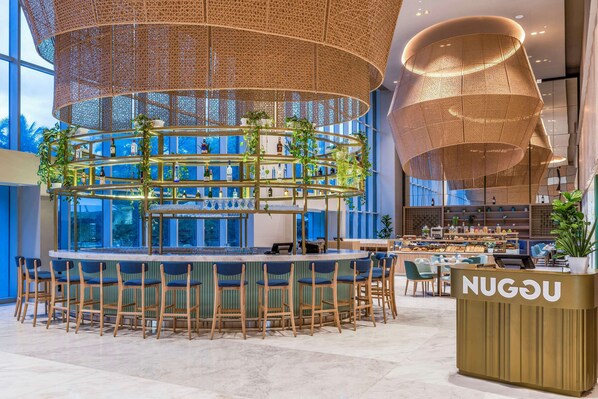 A modern bar area with a circular bar counter, multiple seating options, and a prominent reception desk.