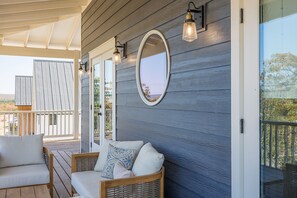 A covered outdoor seating area with wicker furniture and a large mirror on the wall. - Carlton Landing-Charlotte's Nook (Carlton Landing)
