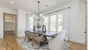 Un coin repas avec une table en bois, des chaises en osier et un canapé blanc.