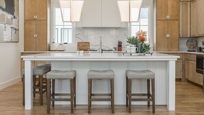 Une cuisine moderne dotée d’un îlot central, de meubles en bois et de luminaires suspendus.