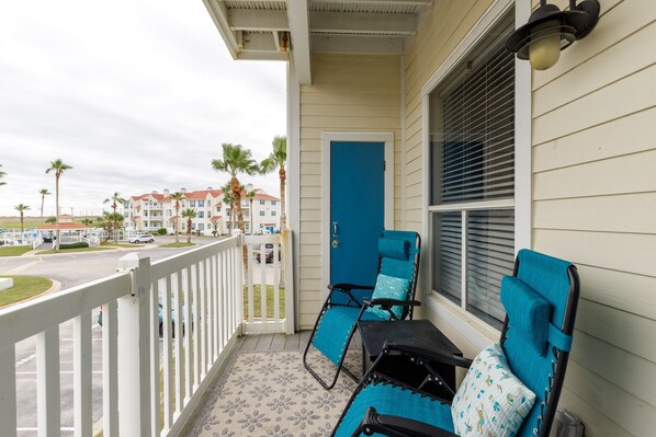 A balcony with two blue chairs and a white railing.