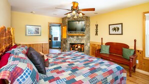 Un dormitorio acogedor con una cama grande, chimenea, televisor y pared de piedra.